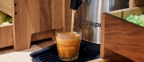 Una cafetera sirviendo café en un vaso.