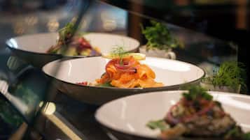 A restaurant with a modern interior, featuring a glass partition and a variety of dishes displayed on plates.