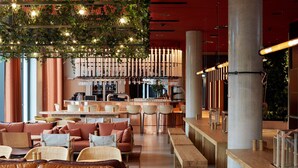 A modern interior with leather sofas, wooden tables, and a bar area with bottles and glasses.