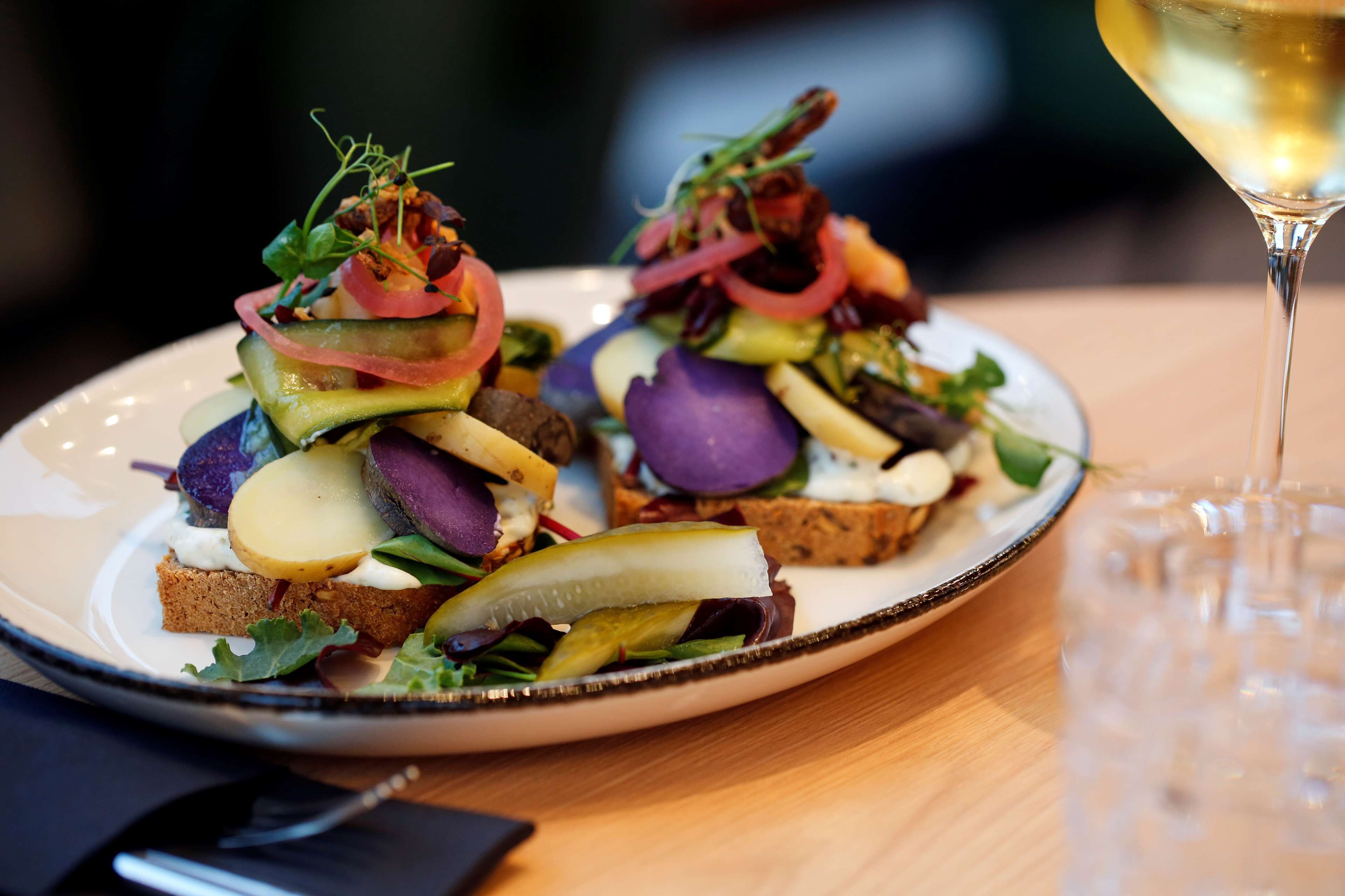 Une assiette de nourriture contenant divers légumes et un verre de vin blanc.