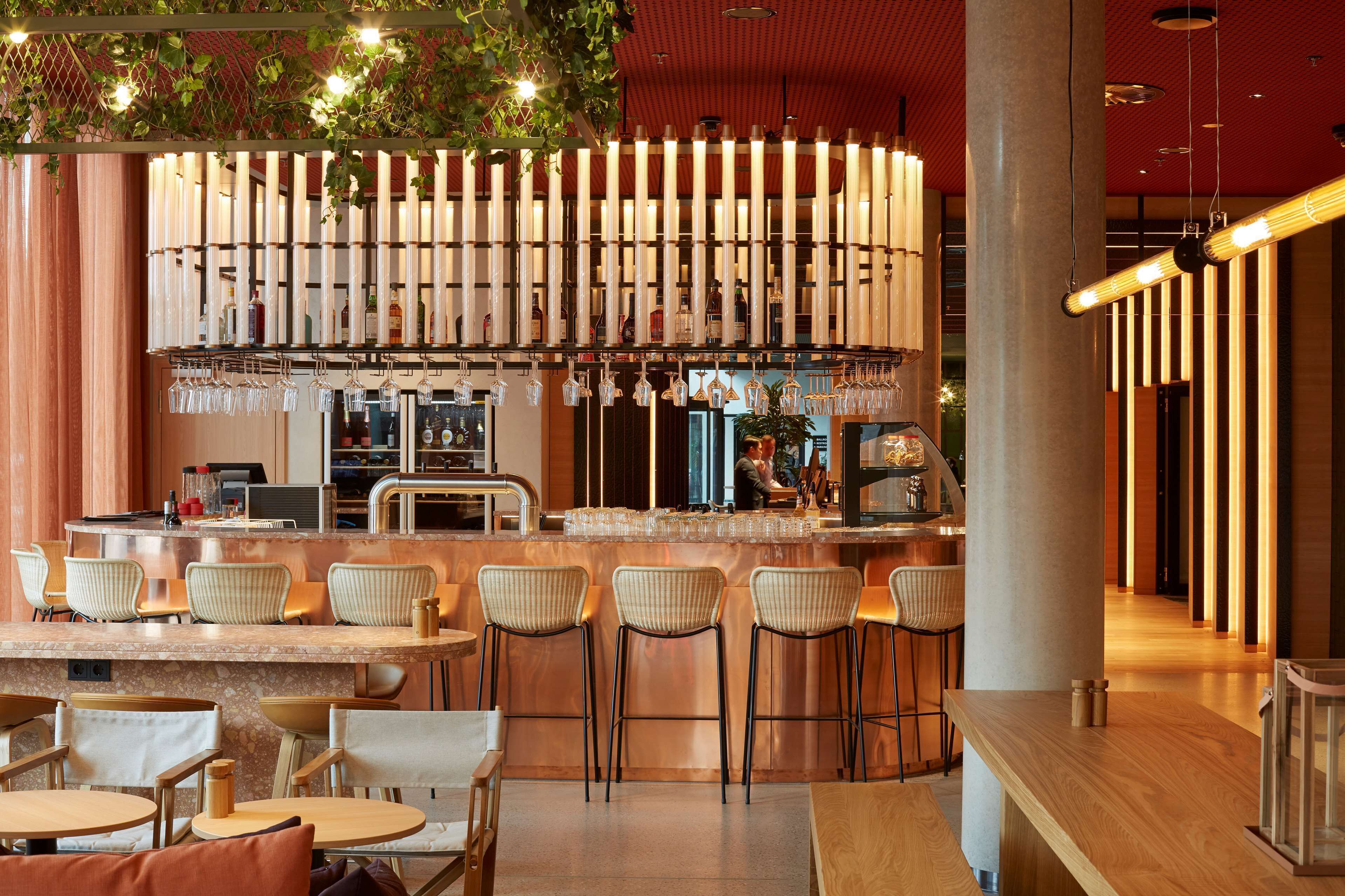 A bar area with a counter, stools, and hanging wine glasses.
