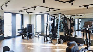 Un gimnasio moderno con diverso equipo de ejercicio, amplias ventanas y suelo de madera.