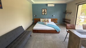 Un dormitorio con cama, un banco, ventilador de techo, ventana y aire acondicionado de pared.