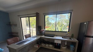 Una cocina con isla integrada, un refrigerador y una ventana con vista a árboles.