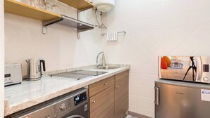 A kitchen with a built-in washing machine, a microwave, and a refrigerator. - Loft Malaga Historic Center (Málaga)
