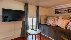A cozy room with a bed, a TV mounted on the wall, a small table with a remote, and a window with curtains. - Loft Malaga Historic Center (Málaga)