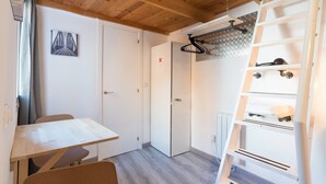 A room with a wooden ceiling, a white door, a table with chairs, a ladder, and a wall-mounted shelf. - Loft Malaga Historic Center (Málaga)