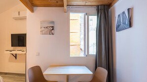 A room with a white table and two chairs, a flat-screen TV, a painting, and a window with curtains. - Loft Malaga Historic Center (Málaga)