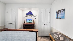 Une chambre à coucher avec un lit, une télévision, un bureau et une chaise.