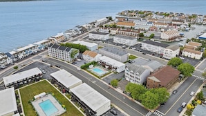 Vue aérienne d’une ville côtière avec un port de plaisance, des immeubles résidentiels et une piscine.