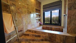 A bathroom with marble walls, a bathtub, and a window with a view of trees. - Resona Pool Villa by Aonanta Group (Krabi)