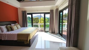 A spacious bedroom with a large bed, a balcony with a view of greenery and mountains, and a sliding glass door. - Resona Pool Villa by Aonanta Group (Krabi)