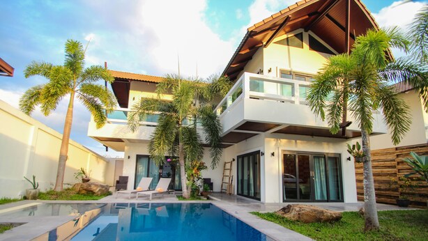 A modern two-story house with a swimming pool, palm trees, and a wooden deck. - Resona Pool Villa by Aonanta Group (Krabi)