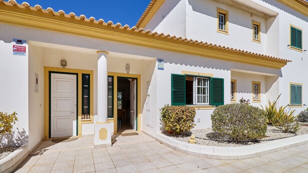 A two-story building with a white facade, green shutters, and a tiled entrance area. - Apartment Diana with pool (Albufeira)
