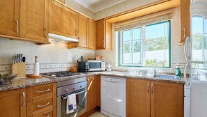 A modern kitchen with wooden cabinets, stainless steel appliances, and a window providing natural light. - Apartment Diana with pool (Albufeira)