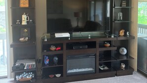 Un soggiorno con un'ampia TV a schermo piatto, scaffalature in legno scuro e un murale a tema golf.