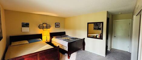 A hotel room with a bed, a desk, a lamp, a calendar, and a mirror.
