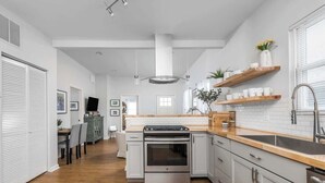 A modern kitchen with a central island, stainless steel appliances, and wooden countertops. - The Little Blue Cottage in Fountain Sq | Walkable! (Indianapolis)