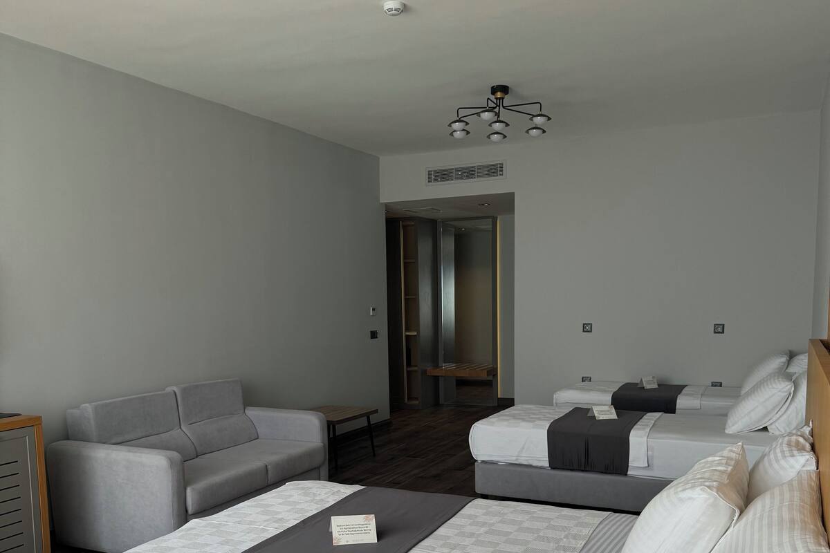 A modern hotel room with a large bed, a sofa, and a desk.