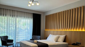Ett hotellrum med två sängar, ett skrivbord, en stol och ett stort fönster med gardiner.