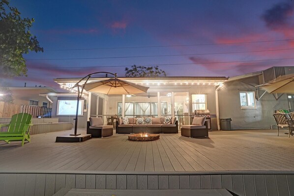 An outdoor patio area with a fire pit, seating, and a covered section with a table and chairs.