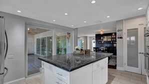 A modern kitchen with white cabinetry, granite countertops, and recessed ceiling lights. - NEW! Spacious Relaxing Home With  Boat Dock (Hollywood)