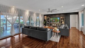 A modern living room with a dark grey sectional sofa, a round wooden coffee table, and a black brick accent wall. - NEW! Spacious Relaxing Home With  Boat Dock (Hollywood)