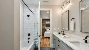 A modern bathroom with a shower, a bathtub, a large mirror, and a vanity with a sink.