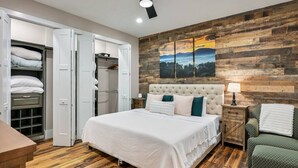 A bedroom with a large bed, wooden flooring, a wardrobe, and a painting on the wall.
