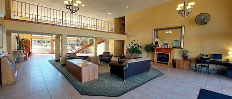 A spacious lobby with a high ceiling, a staircase, and a fireplace.