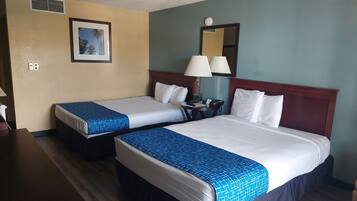 Habitación de hotel con dos camas, un escritorio, una lámpara y un cuadro en la pared.