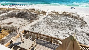 A beach view with a wooden deck, outdoor seating, and a tent. - On the Beach, Big Deck, Chair Service, Steps onto the Sand (Miramar Beach)