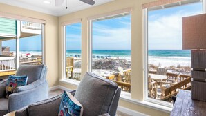 A room with a large window overlooking a beach, a ceiling fan, and a view of beach chairs and umbrellas. - On the Beach, Big Deck, Chair Service, Steps onto the Sand (Miramar Beach)