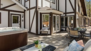 Ein modernes Haus mit einer Terrasse, einem Whirlpool, Sitzgelegenheiten im Freien und einer Holzterrasse.