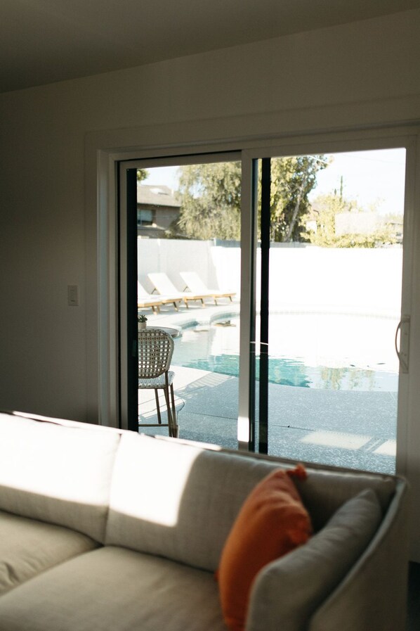 Relax in a comfortable, contemporary living space with an outdoor area featuring a pool and lounge chairs.