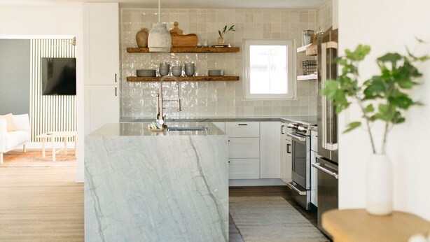 Une cuisine moderne avec des meubles blancs, un îlot en marbre et des appareils électroménagers en acier inoxydable.