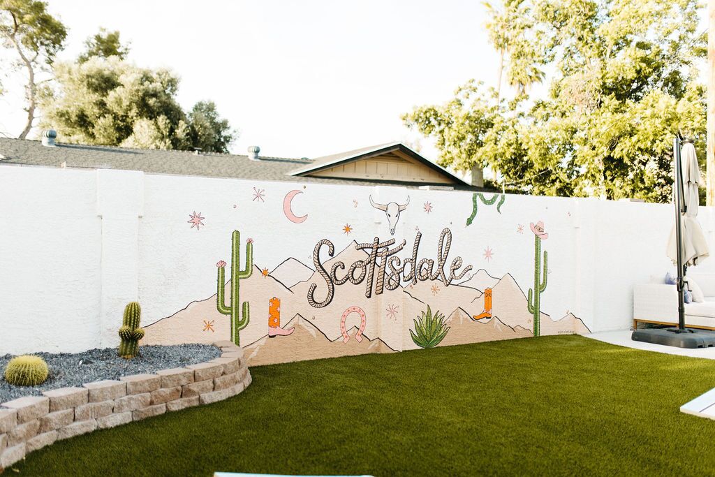 A wall mural with a desert theme, including cacti and a cow, and the word "Scottsdale".