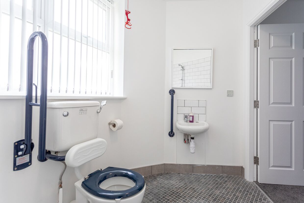 A small bathroom with a toilet, a sink, and a window.