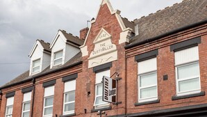 Une rangée de maisons mitoyennes, avec une enseigne bien visible indiquant « The Dusty Millers » et une autre, plus petite, indiquant « Dusties Lodge ».