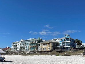 Una proprietà fronte spiaggia con edifici a più piani, una spiaggia sabbiosa e un cielo azzurro limpido.
