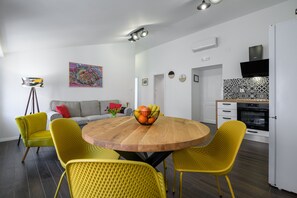 Une cuisine moderne avec une table à manger en bois, des chaises jaunes et un panier de fruits.