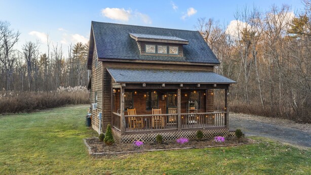 Une cabane en bois avec un porche, une terrasse couverte et un petit jardin fleuri.