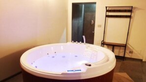 Una banyera d'hidromassatge en una habitació amb terra de fusta i una porta al fons.