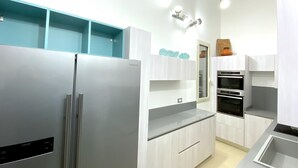A modern kitchen with a stainless steel refrigerator, built-in oven, and white cabinetry. - Villa La Maddalena in La Maddalena (La Maddalena)