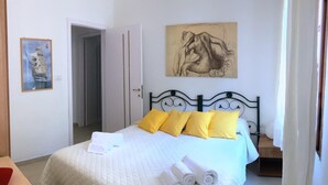 A bedroom with a bed, a painting, and a door leading to another room. - Villa La Maddalena in La Maddalena (La Maddalena)