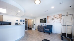 A reception area with a curved counter, a television mounted on the wall, and a cart. - Independence Stay (Houghton)