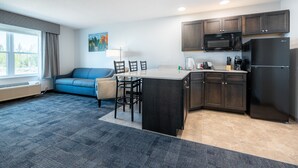 A compact living space with a kitchenette, a sofa, a dining area, and a large window providing natural light. - Independence Stay (Houghton)