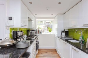 A modern kitchen with white cabinets, a granite countertop, a coffee maker, and a window with a view of greenery.