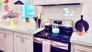 Una cocina moderna con armarios blancos, una estufa negra y un ventanal con vistas al verdor.