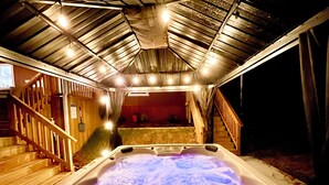 Jacuzzi amb una escala de fusta que condueix a una zona de terrassa, sota una estructura de teulat metàl·lic.